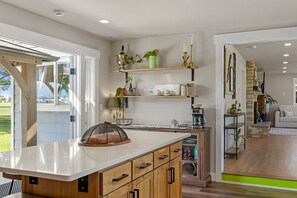 Eine moderne Küche mit Holzschränken, einer Marmorarbeitsplatte und einem eingebauten Backofen.