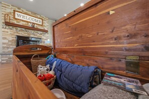 Ein gemütliches Zimmer mit einem hölzernen Bett, einem Willkommensschild, einem Kamin und einem Korb mit Gegenständen.