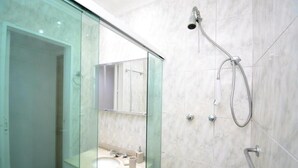 Un baño moderno con ducha envuelta en vidrio, lavamanos y cabezal de ducha de mano.