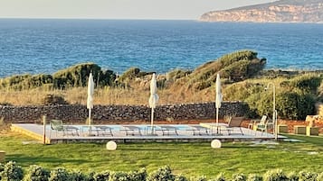 Una piscina al aire libre de temporada, sombrillas, tumbonas