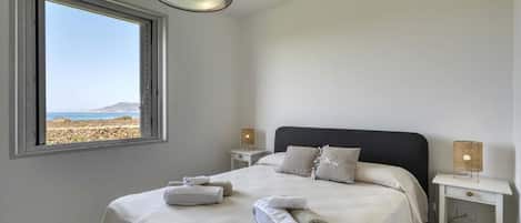A hotel room with a bed, two bedside tables, a window with a view, and a ceiling light.