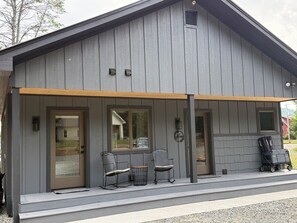 A modern building with a covered porch, two doors, and a small table with chairs.