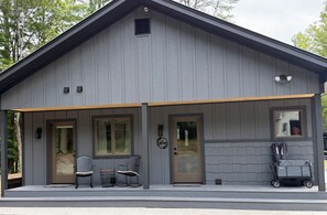 A two-story building with a covered porch, two doors, and a small window.