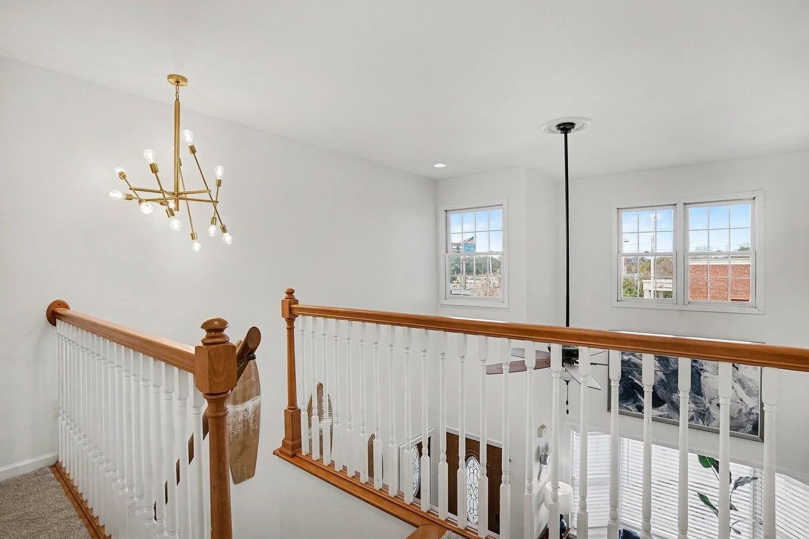 A staircase with a wooden handrail and white balusters, leading to a balcony with a view of the city.