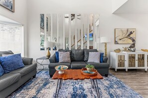 A modern living room with a grey sofa, a wooden coffee table, and a blue patterned rug. - Designer Family Beach House · Walk to Sand & Golf (North Myrtle beach)