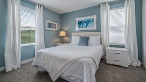 A bedroom with a bed, nightstands, a lamp, and two framed pictures on the wall. - 8-bedroom House - Championsgate With Pool (Davenport)