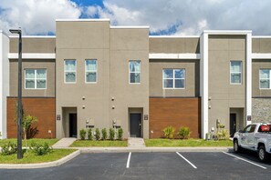 A multi-story residential building with a parking lot in front. - Modern 5BR Home Near Disney With Private Pool (Davenport)
