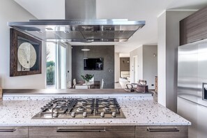 Una cocina moderna con una campana extractora de acero inoxidable, una estufa a gas y un refrigerador.