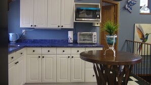 A kitchen with white cabinets, a microwave, a toaster, and a potted plant on the counter.