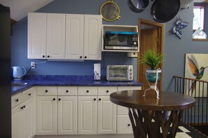 A kitchen with white cabinets, a microwave, a toaster, and a potted plant on the counter.