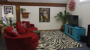 A living room with a red sofa, a zebra-patterned rug, a blue cabinet, and a television.