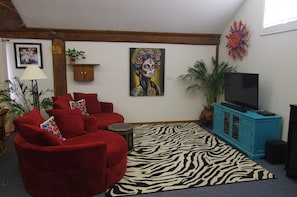 A living room with a red sofa, a zebra-patterned rug, a blue cabinet, and a television.