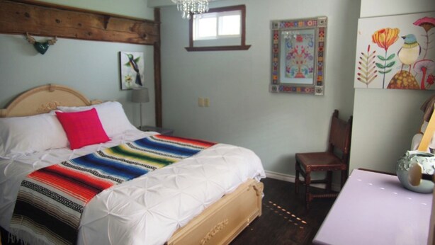 A bedroom with a bed, a chair, a table, and wall decorations.