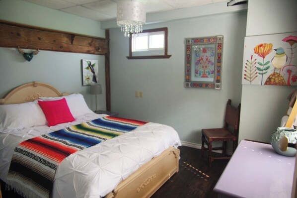 A bedroom with a bed, a chair, a table, and wall decorations.