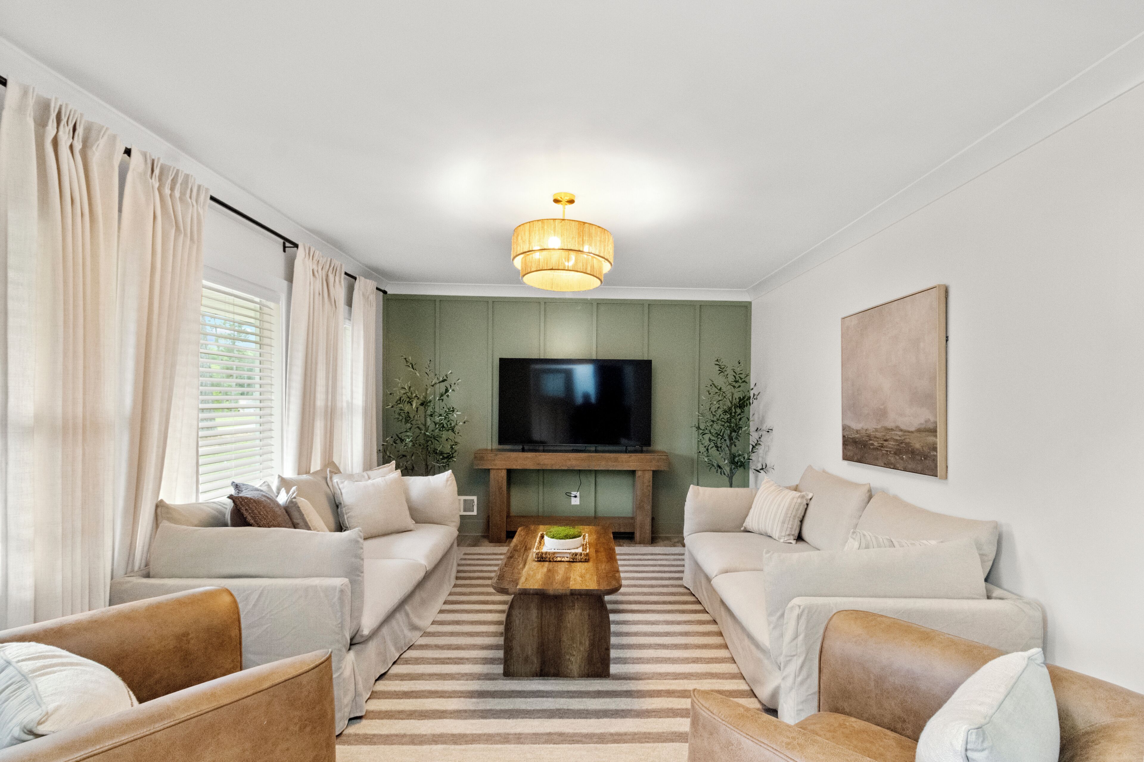 A modern living room with a flat-screen TV, two sofas, a coffee table, and a striped rug.