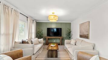 A modern living room with a flat-screen TV, two sofas, a coffee table, and a striped rug.