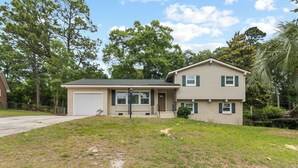 A two-story house with a garage, a front porch, and a well-maintained lawn.