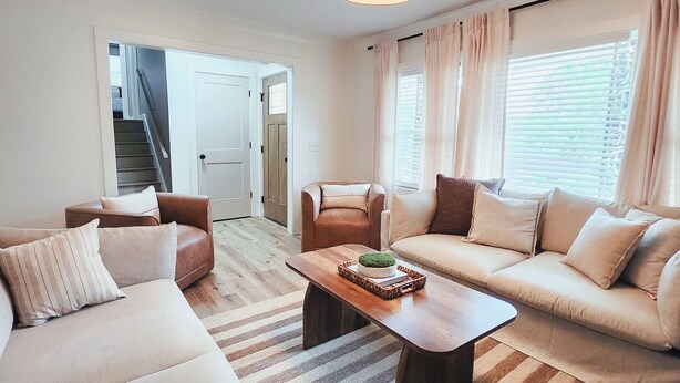 A living room with a sofa set, a coffee table, and a staircase leading to another room.