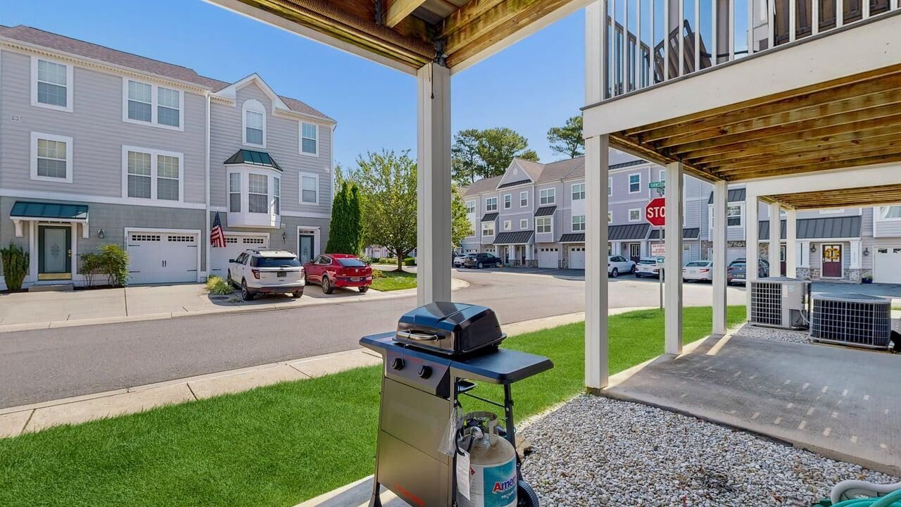 A residential street with houses, a barbecue grill, and a stop sign.