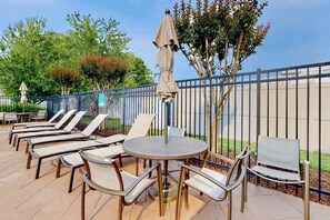 An outdoor seating area with lounge chairs and a round table, surrounded by a metal fence. - Rehoboth Crossing - 36983 Grindstone Ln. (Rehoboth Beach)