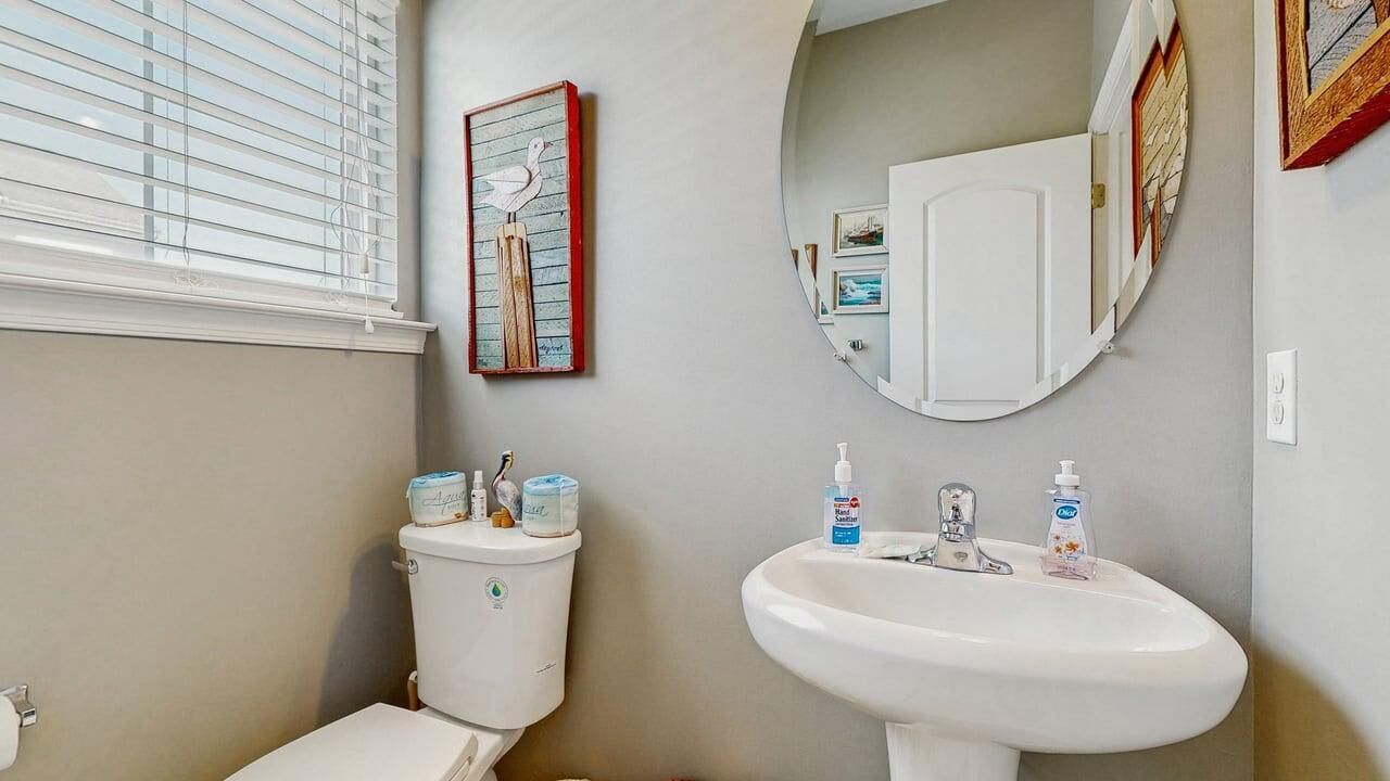 Een badkamer met toilet, wastafel en spiegel.
