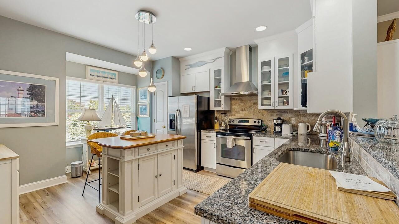 A modern kitchen with white cabinetry, stainless steel appliances, and a granite countertop.