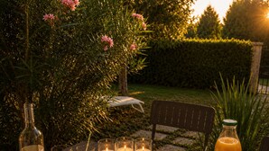 A table set outdoors with a bottle of wine, glasses, candles, a fruit platter, and a bottle of orange juice. - The Butterfly Garden (La Buisse)