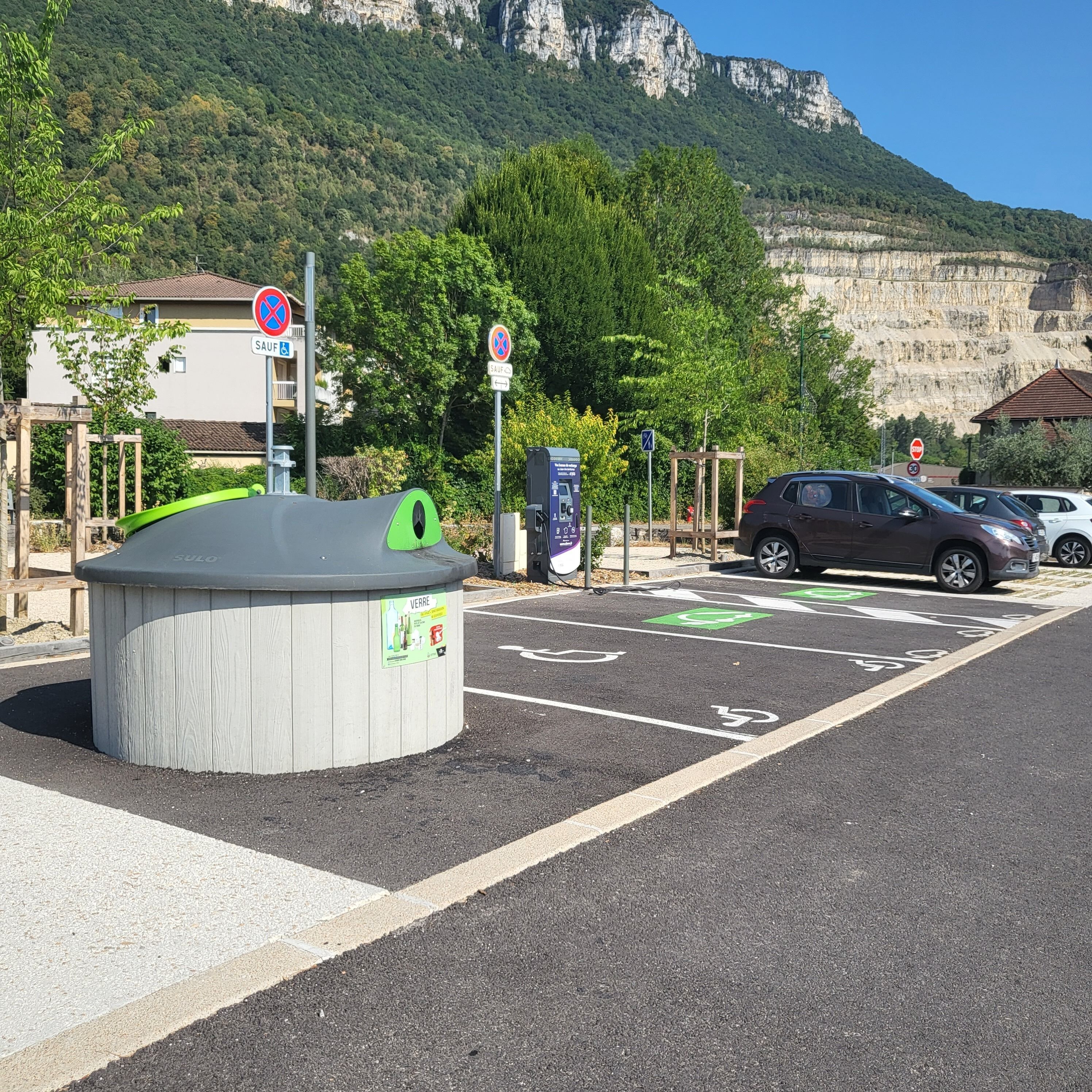 A parking area with electric vehicle charging stations, marked bicycle lanes, and a stop sign.
