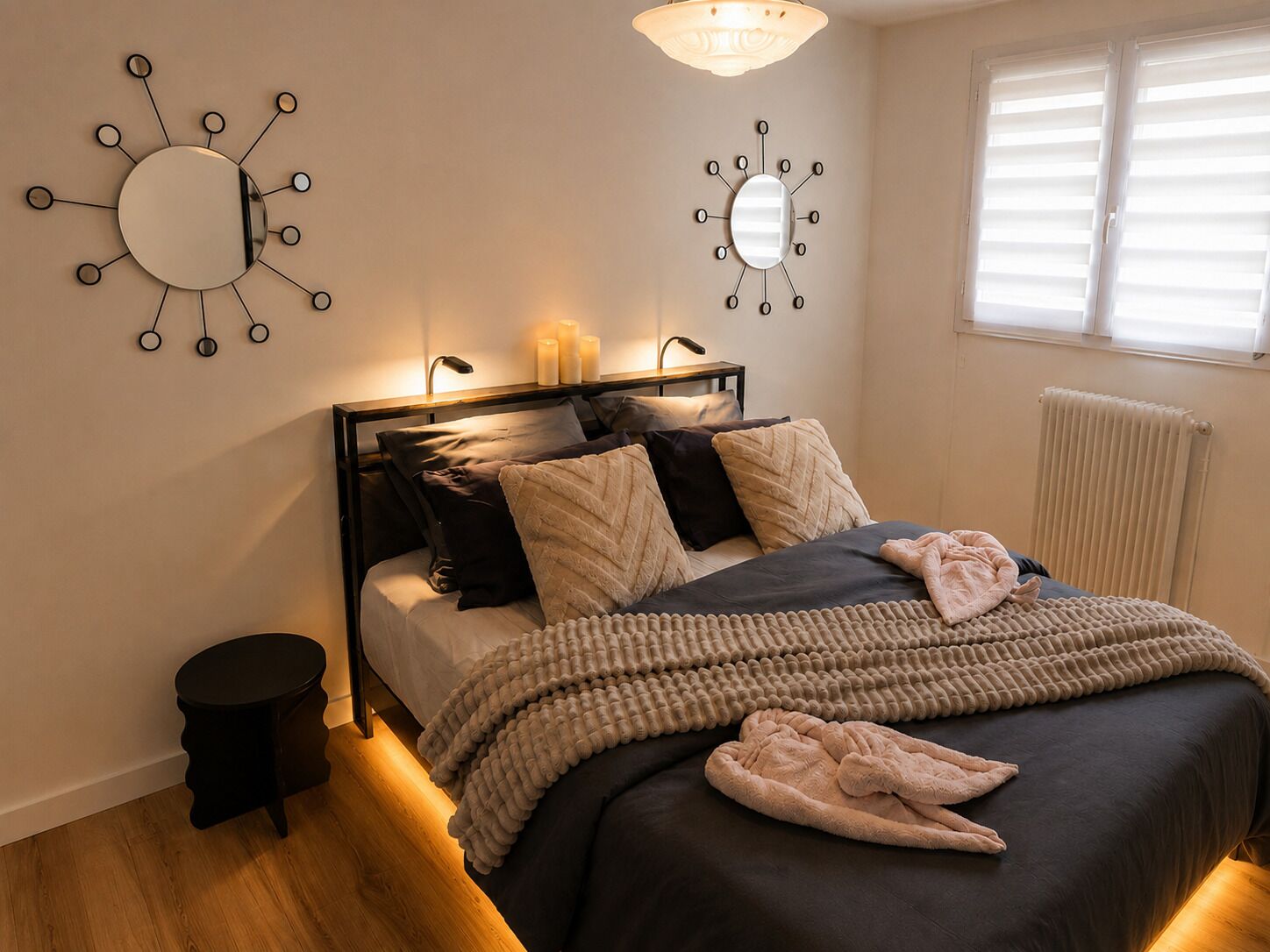 Ein Schlafzimmer mit einem Bett, Nachttischlampen, einem runden Spiegel und einer Heizung.