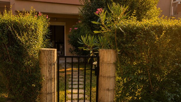 A gated entrance with a stone pathway leading to a building. - The Butterfly Garden (La Buisse)