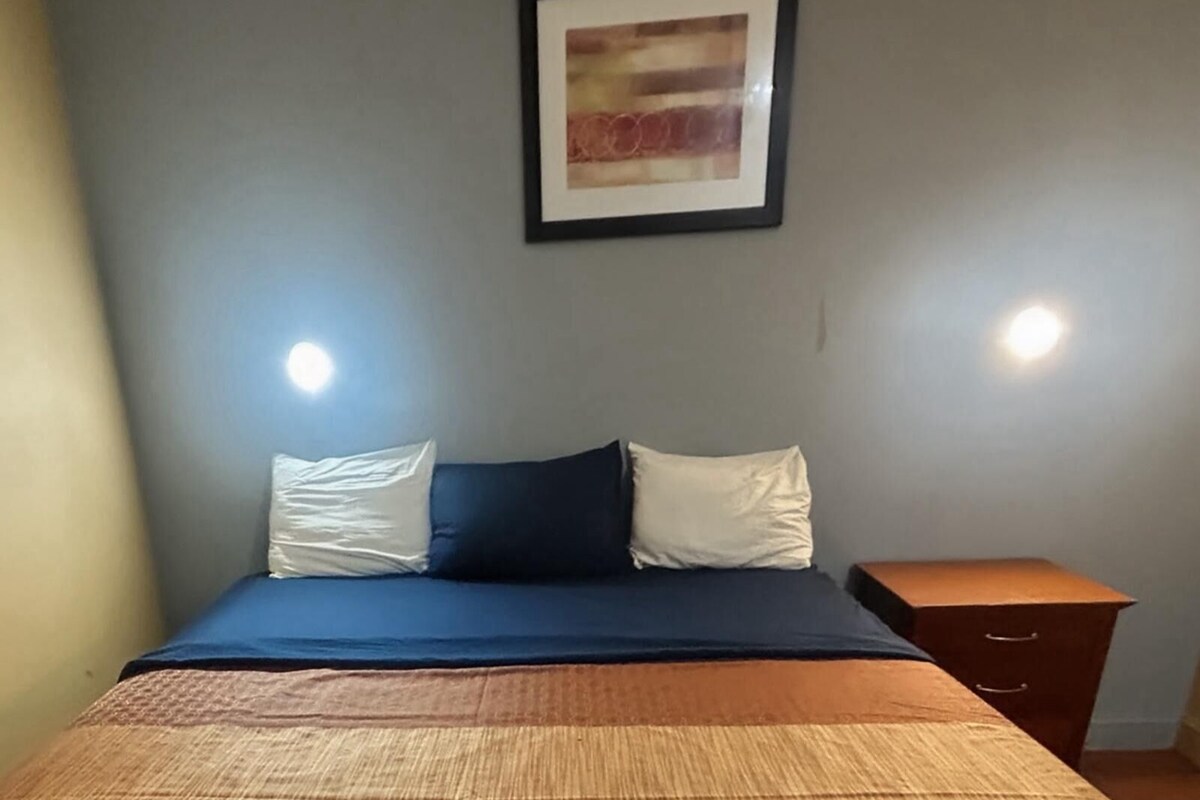 A room with a bed, a nightstand, and a framed picture on the wall.
