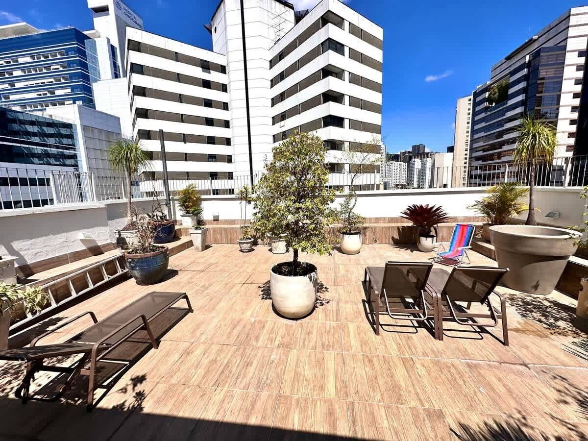An outdoor terrace with a seating area, potted plants, and a view of surrounding buildings.