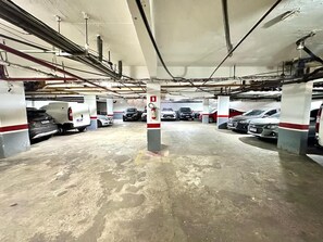 Eine mehrstöckige Parkgarage mit mehreren parkenden Autos, Betonböden und sichtbaren Stahlträgern.