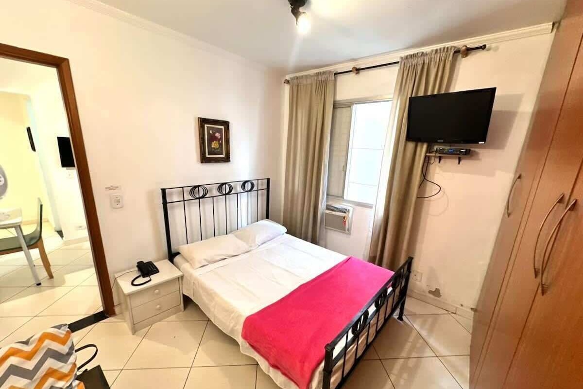 Ein Schlafzimmer mit einem Bett, einem Nachttisch, einem Fernseher und einem Kleiderschrank.