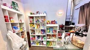Kapea käytävä, jonka seinillä on hyllyjä, joilla on erilaisia elintarvikkeita, ja lasivitriini, jossa on kori täynnä leipää.