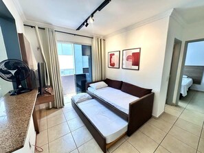Ein Hotelzimmer mit einem Bett, einem Schreibtisch, einem Stuhl, einem Ventilator und einem Fenster.