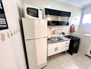 Una cocina compacta con un refrigerador blanco, un microondas, una estufa y un lavaplatos.