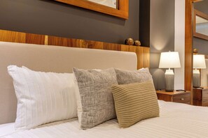 A bed with three pillows, a wooden headboard, and two bedside lamps. - Two Condos | Ideal for Families & Groups (Cabo San Lucas)