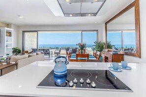 Une cuisine moderne dotée d’un grand îlot central, d’une bouilloire et offrant une vue sur l’océan.