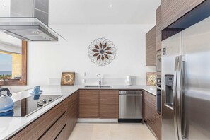 Une cuisine moderne équipée d’un réfrigérateur en acier inoxydable, d’un lave-vaisselle et d’un élément décoratif mural.