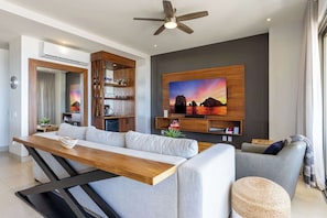 A modern living room with a sofa, a dining table, and a kitchen area. - Two Condos | Ideal for Families & Groups (Cabo San Lucas)