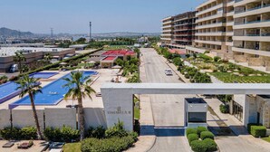 A hotel with a swimming pool, a parking area, and a view of the cityscape. - Two Condos | Ideal for Families & Groups (Cabo San Lucas)