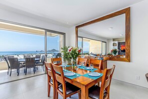 A dining area with a view of the sea, a large mirror, and a table set for four. - Two Condos | Ideal for Families & Groups (Cabo San Lucas)