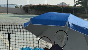A tennis court with a cart containing rackets, balls, and towels. - Two Condos | Ideal for Families & Groups (Cabo San Lucas)