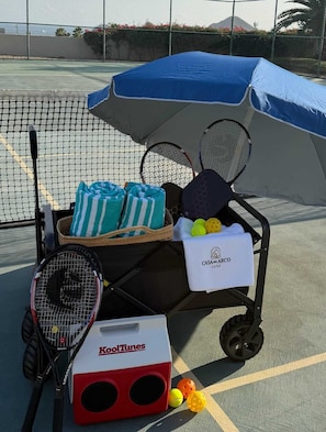 A tennis court with a cart containing rackets, balls, and towels. - Two Condos | Ideal for Families & Groups (Cabo San Lucas)