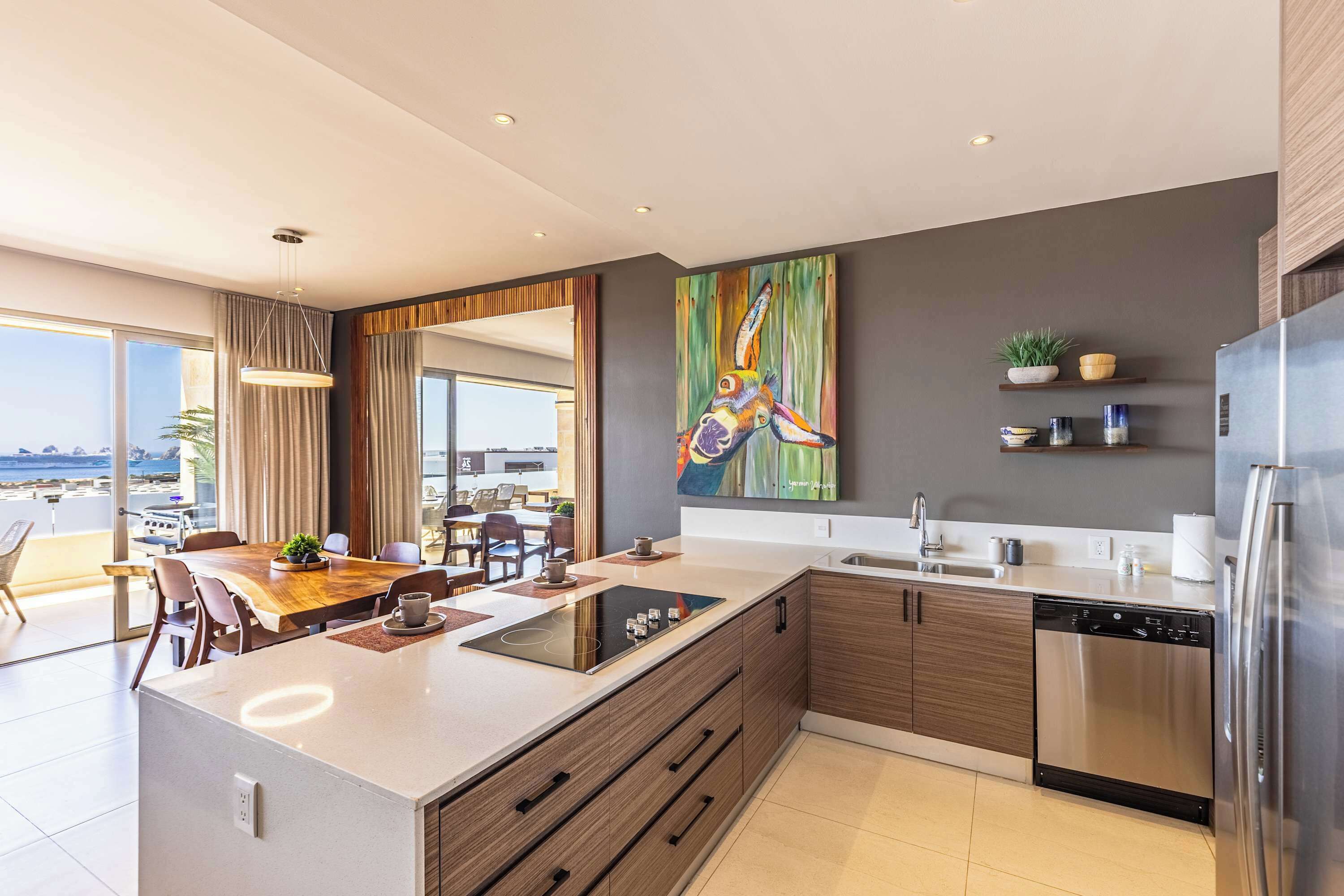 Een moderne keuken met een centraal eiland, inbouwapparatuur en een groot raam met uitzicht op een mooi landschap.