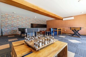 A room with a chessboard, a pool table, a television, and a blue sofa. - Two Condos | Ideal for Families & Groups (Cabo San Lucas)
