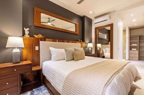 A hotel room with a large bed, bedside tables, a mirror, and a wardrobe. - Two Condos | Ideal for Families & Groups (Cabo San Lucas)