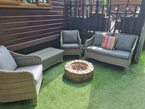 A patio area with wicker furniture and a stone fire pit.