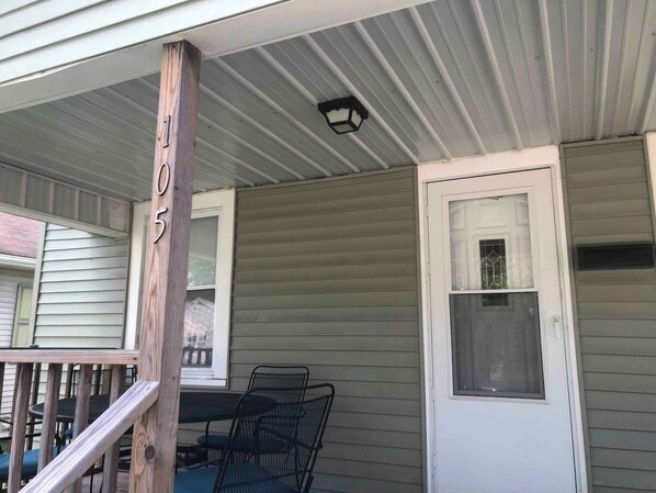 A porch with a wooden post, a metal chair, and a door with a window. - Right off of Main St in Robinson (Robinson)